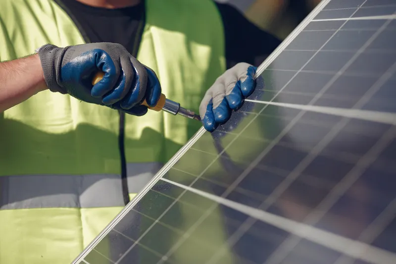 Manos con guantes trabajando sobre una placa solar
