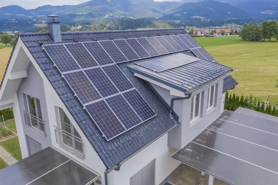 Tejado de una vivienda unifamiliar cubierto de placas solares junto a un prado